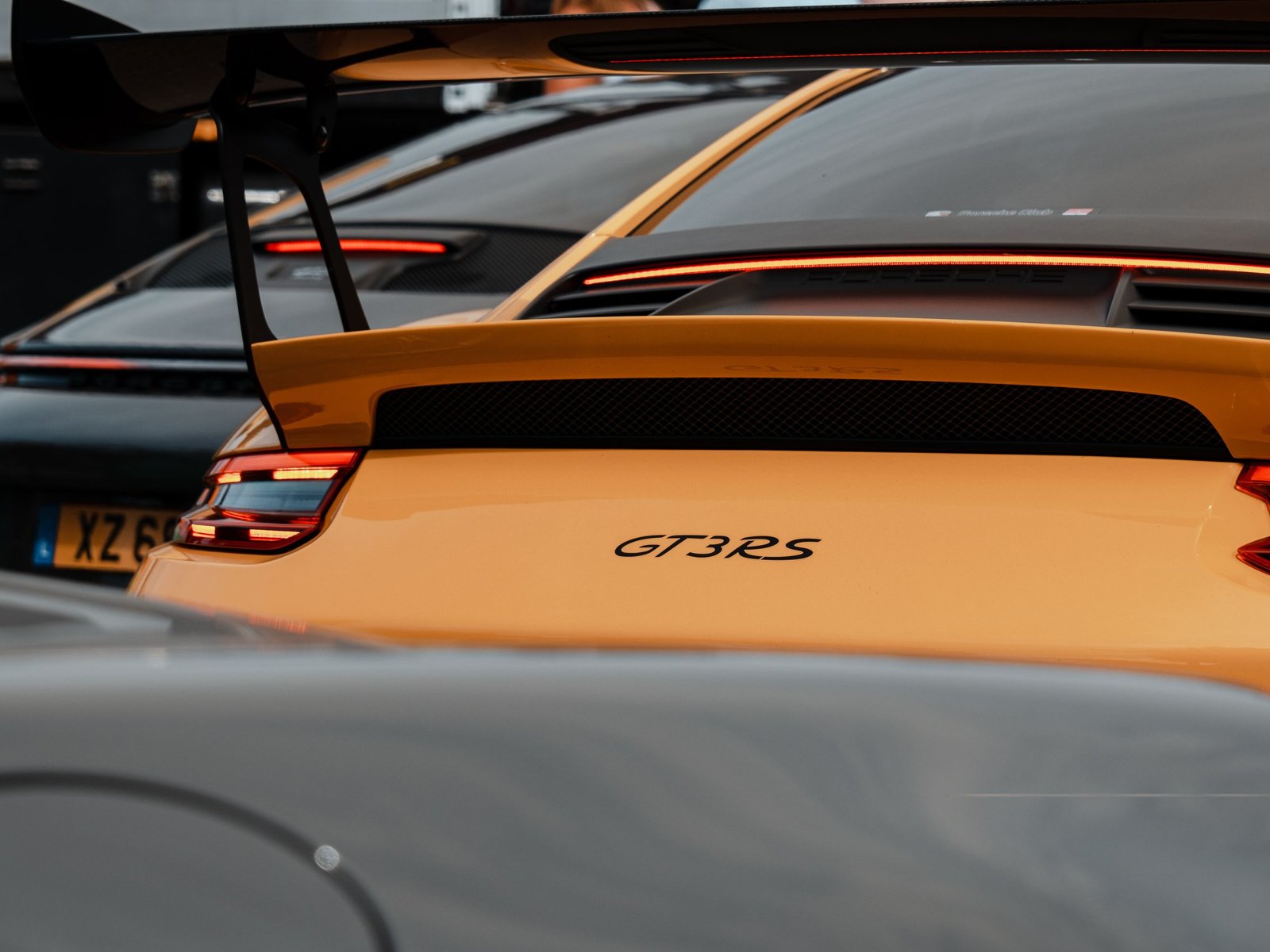 Porsche 911 GT3 RS 992 blanche sur circuit, aileron imposant et jantes dorées, vue de trois quarts avant.