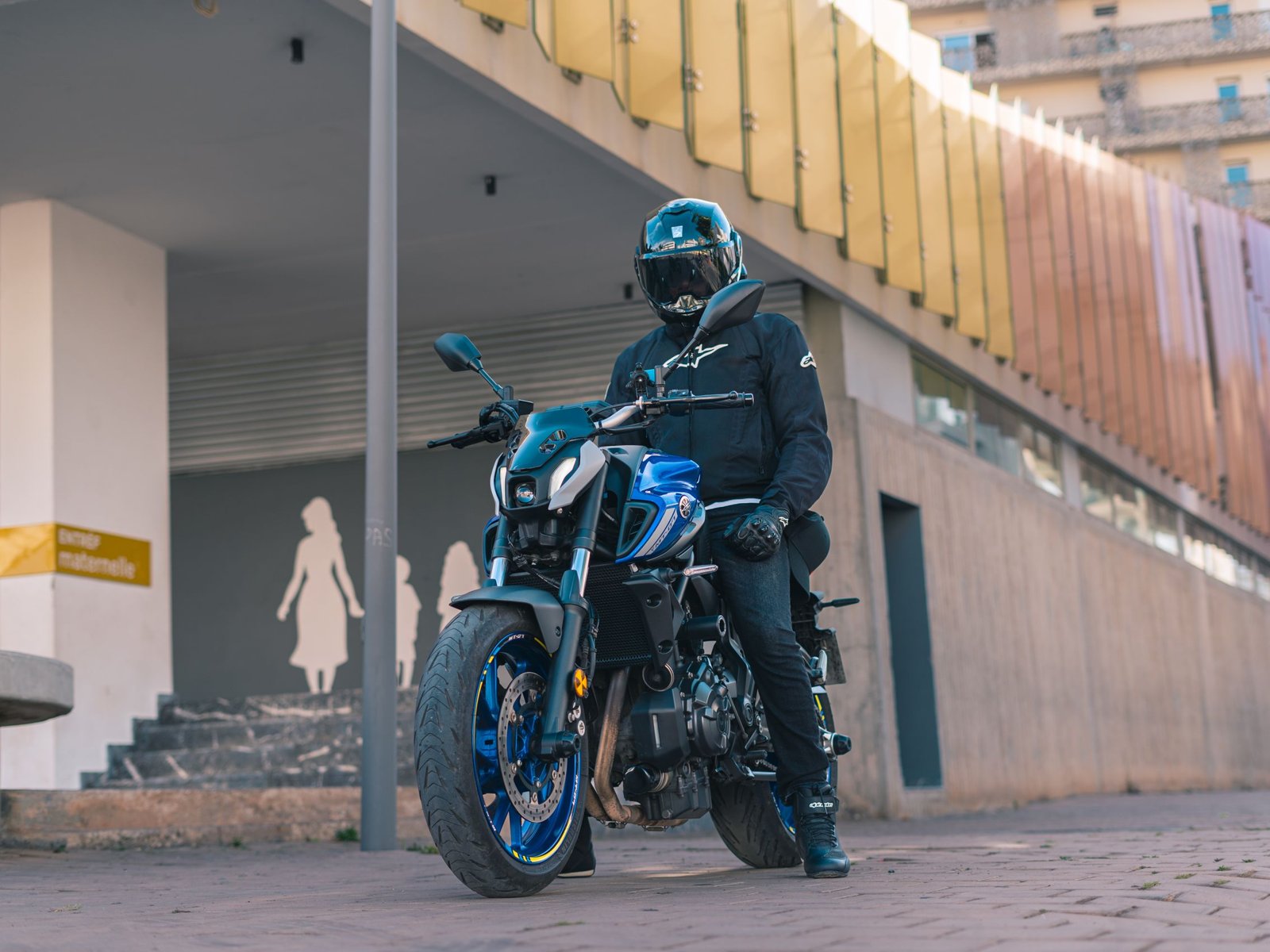 Yamaha MT-07 2025 vue de trois quarts avant, coloris bleu, sur une route de campagne au soleil couchant